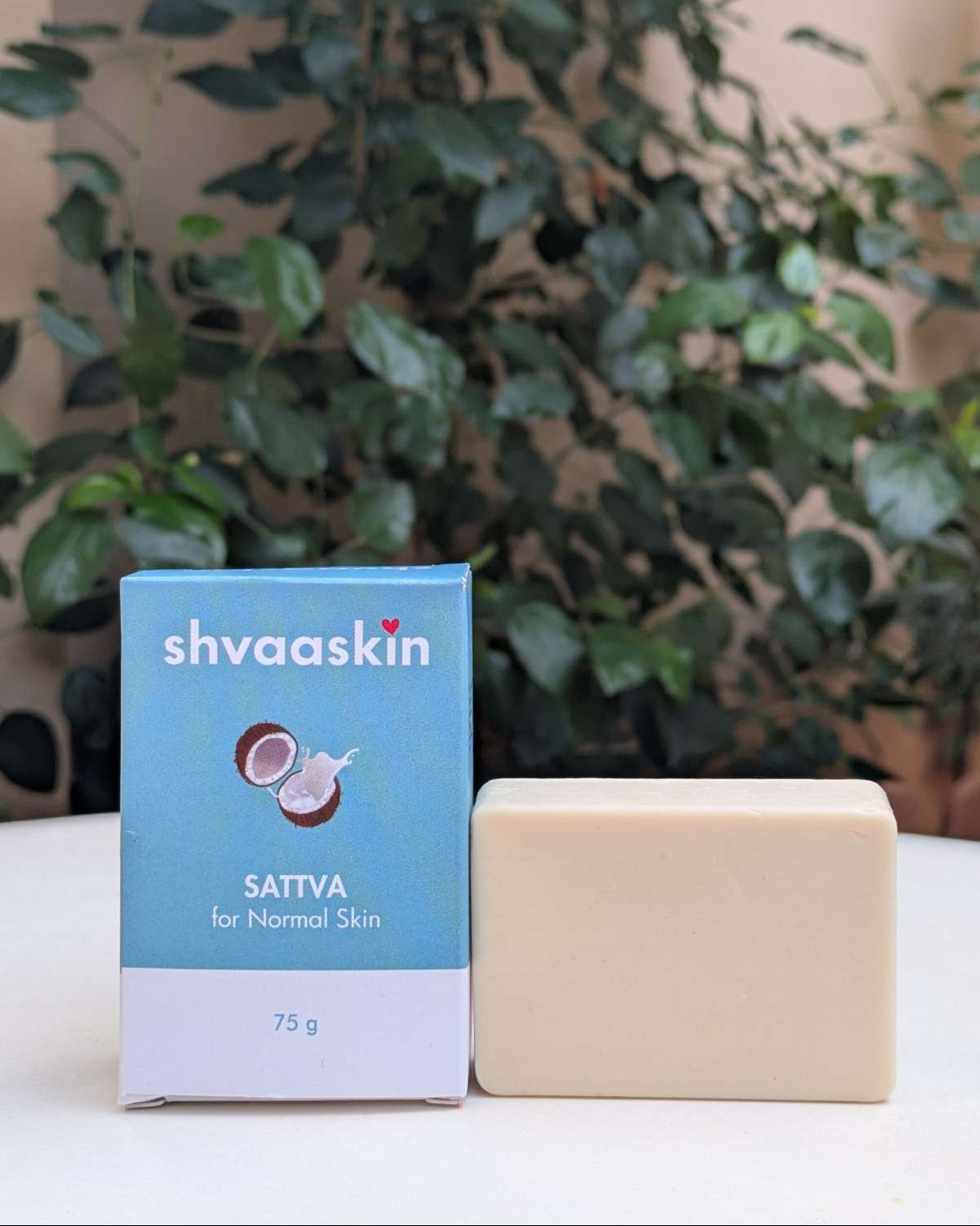 Shvaaskin Sattva soap bar and packaging on a white surface with a green leafy background